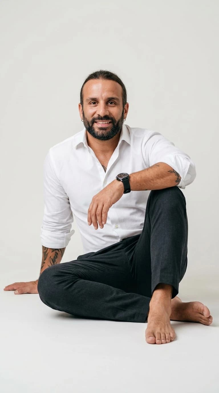 Vartan Escopel sitting on the floor in a white shirt, smiling at the camera